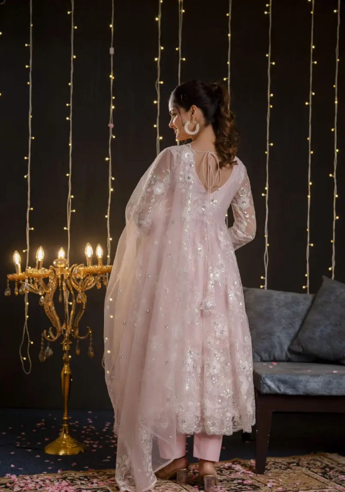 A model wearing a pastel pink embroidered net Anarkali set with matching dupatta and straight pants from Pahraav by Karishma, featuring ¾ sleeves and delicate thread work embroidery, styled for festive and wedding occasions