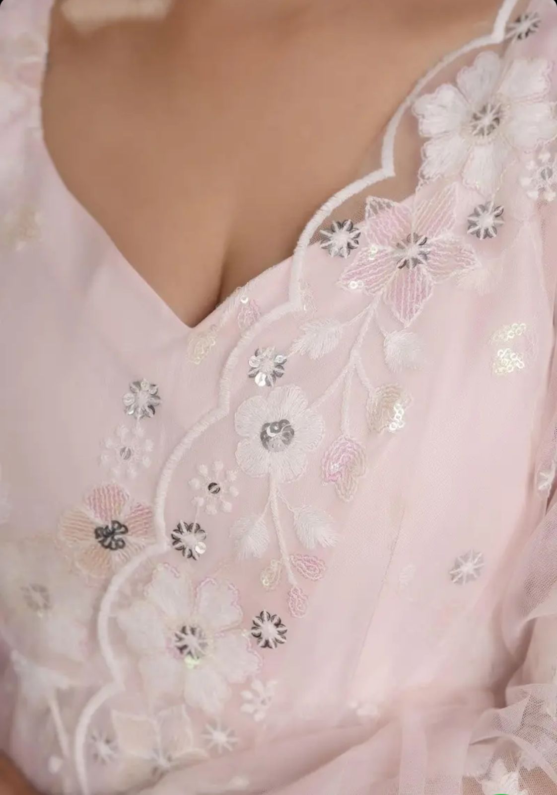 Close-up of a pink dress with floral embroidery and sequins.