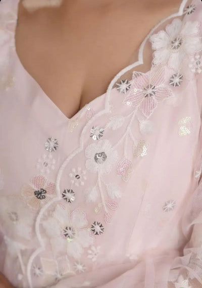 Close-up of a pink dress with floral embroidery and sequins.