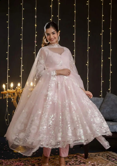Woman in a pink traditional outfit with a dark background and string lights