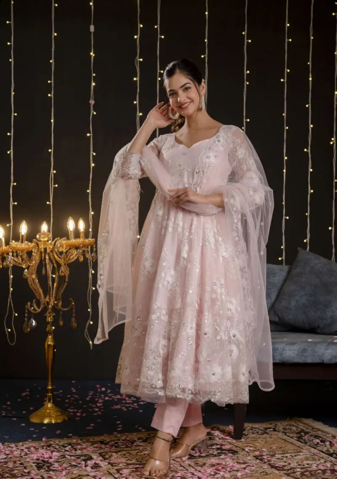 A model wearing a pastel pink embroidered net Anarkali set with matching dupatta and straight pants from Pahraav by Karishma, featuring ¾ sleeves and delicate thread work embroidery, styled for festive and wedding occasions