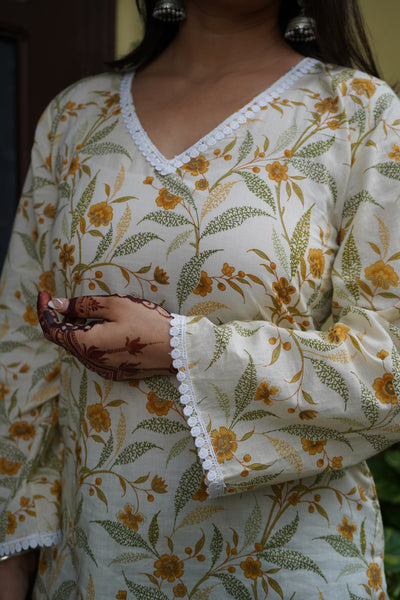 Floral cotton kurti with yellow flower print, V-neck lace detailing, and bell sleeves – Vasanti by Pahraav